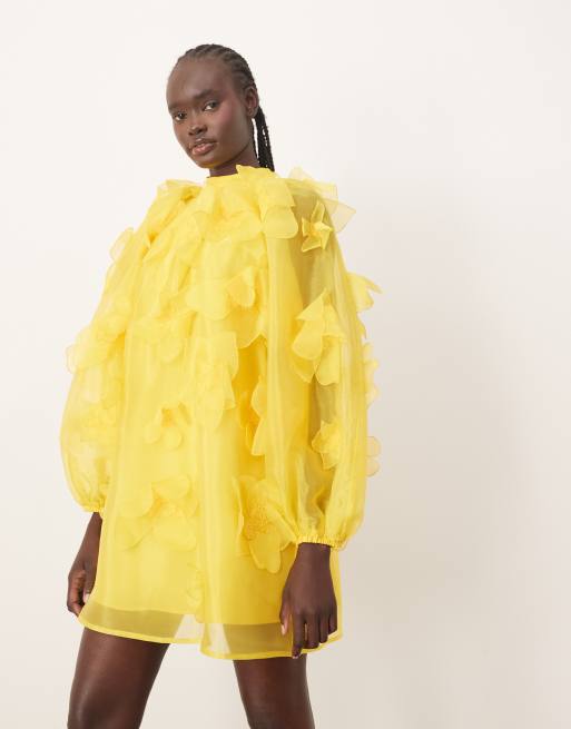 Vestido corto amarillo de corte trapecio con aplicaciones de flores y cuello alto de organza de ARRANGE