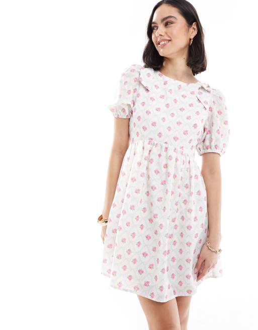 Vestido corto color crema de corte amplio con estampado de florecitas, lazada trasera, mangas abullonadas y lazos en los hombros exclusivo de The Frolic  