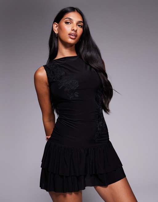 Vestido corto negro ceñido con cuello barco, espalda escotada, bajo de volantes y aplicación floral de tejido ajustado doble de Fashionkilla