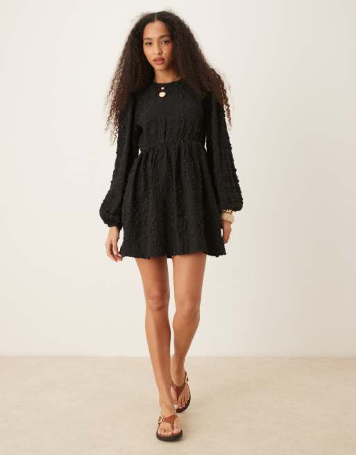 Vestido corto negro con mangas voluminosas, abertura en la espalda y lazada de tejido texturizado de Gina Tricot