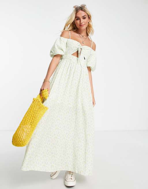 Vestido largo amarillo con hombros descubiertos, lazada delantera, abertura y estampado de florecitas de Sisters of the Tribe