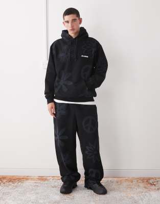 Jogginghose in Schwarz mit Bündchen und Peace- und Logoprint, Kombiteil Schwarz W33-34