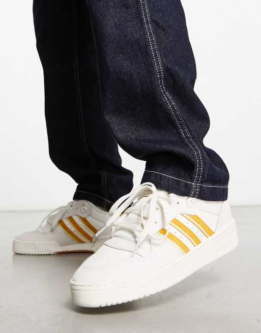 Zapatillas de deporte bajas blancas y doradas Rivalry Low de adidas Originals