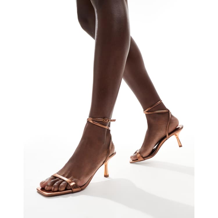 Zapatos color bronce de tacón con diseño cruzado en el tobillo de